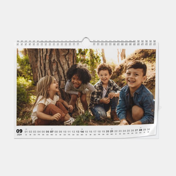 Fotokalender im A4-Querformat auf Seidenraster-Fotopapier zeigt vier lachende Kinder spielend im Wald.