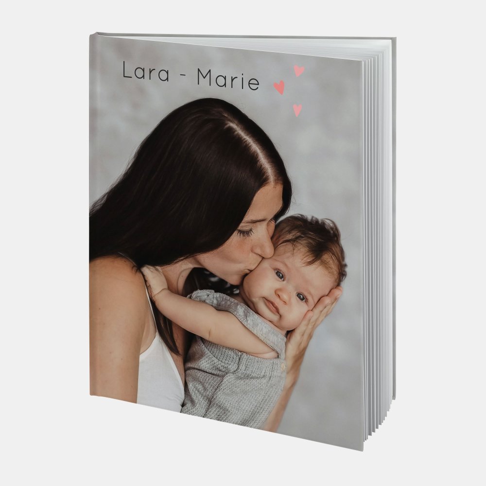 Das Fotobuch A4 hoch zeigt eine Mutter, die ihr Baby liebevoll küsst – ideal für emotionale Baby-Fotobuch-Erinnerungen.