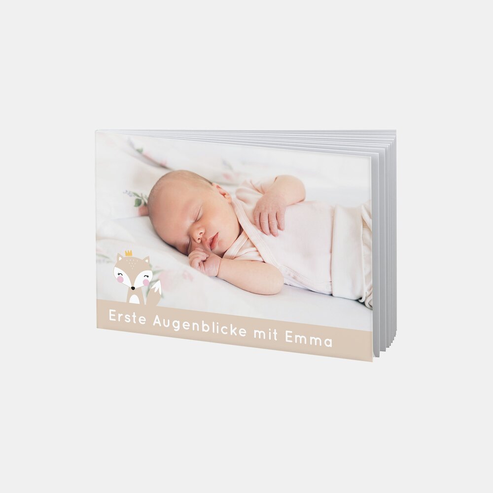 Das RUCK ZUCK Fotobuch® zeigt ein neugeborenes Baby namens Emma, das friedlich schlafend auf einer Decke liegt.