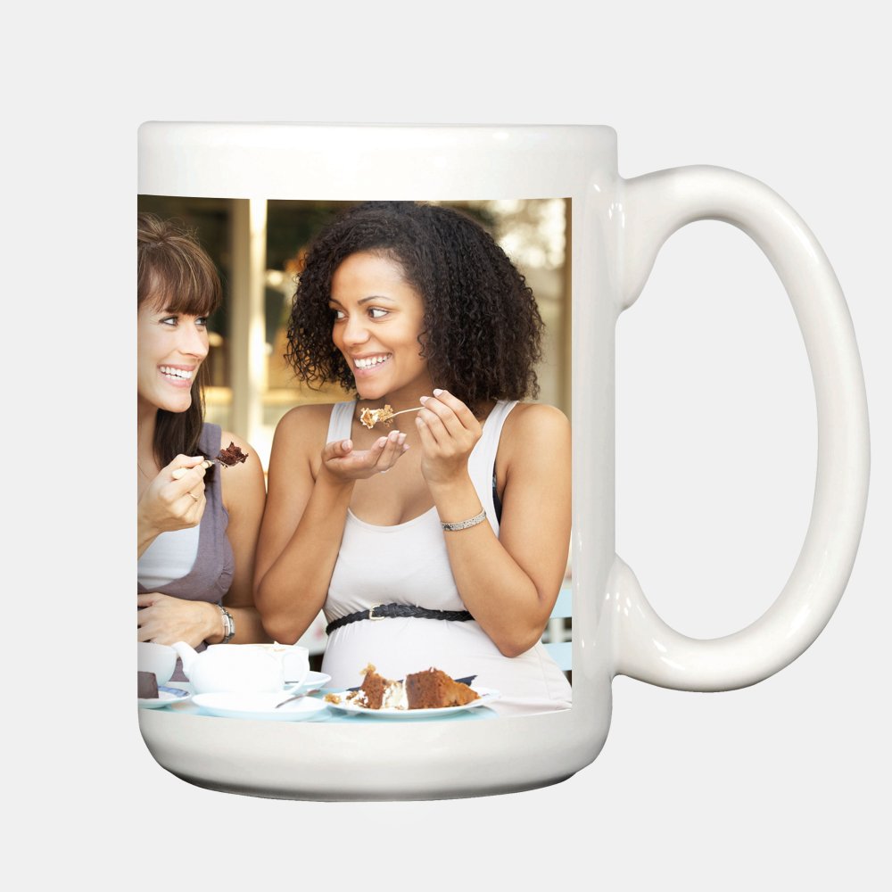 Die personalisierte Fototasse zeigt zwei lachende Frauen beim Kaffeetrinken und Kuchenessen in einem Straßencafé.