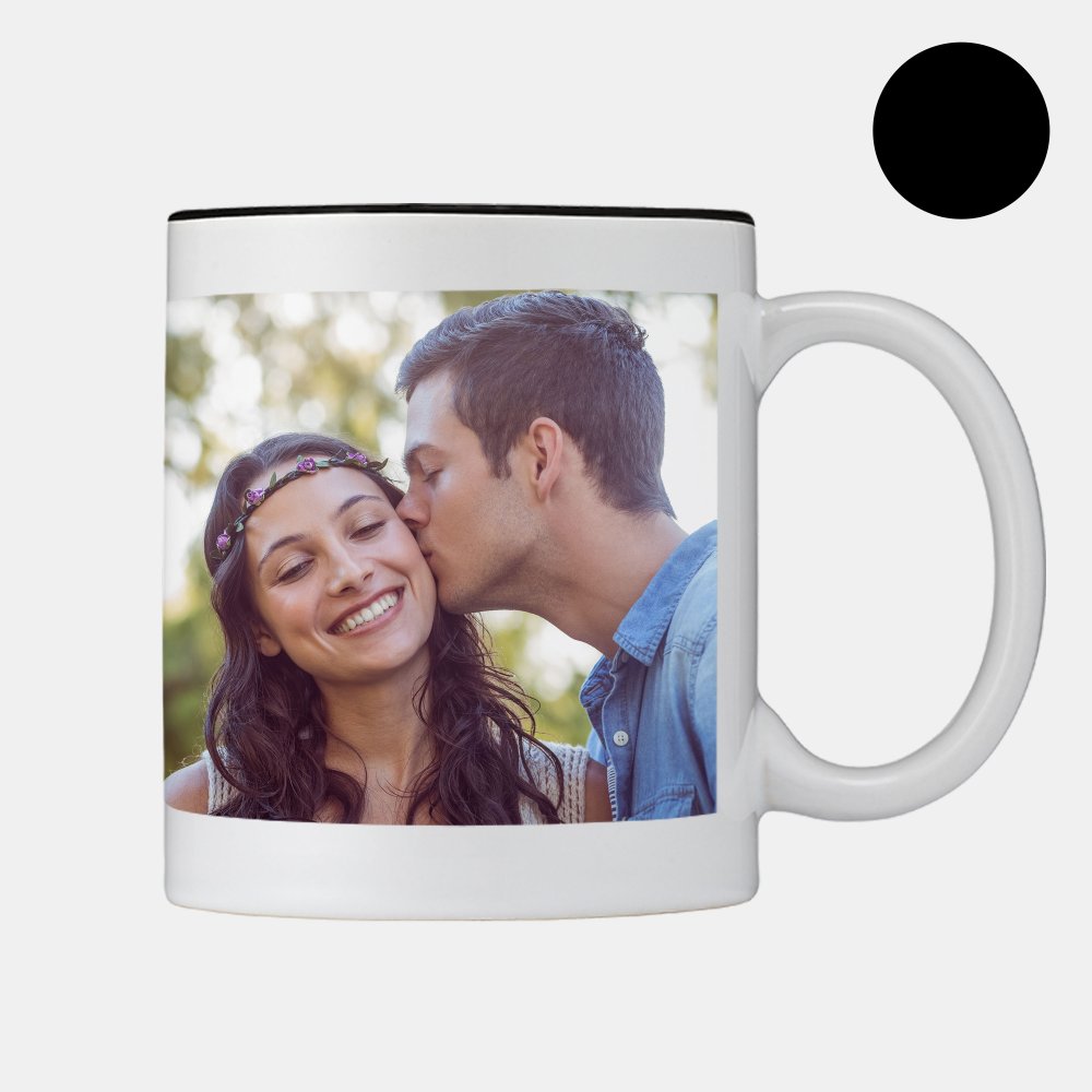 Auf der Tasse mit schwarzem Rand küsst ein Mann eine Frau auf die Wange, daneben zeigt ein schwarzer Kreis die Farbe an.