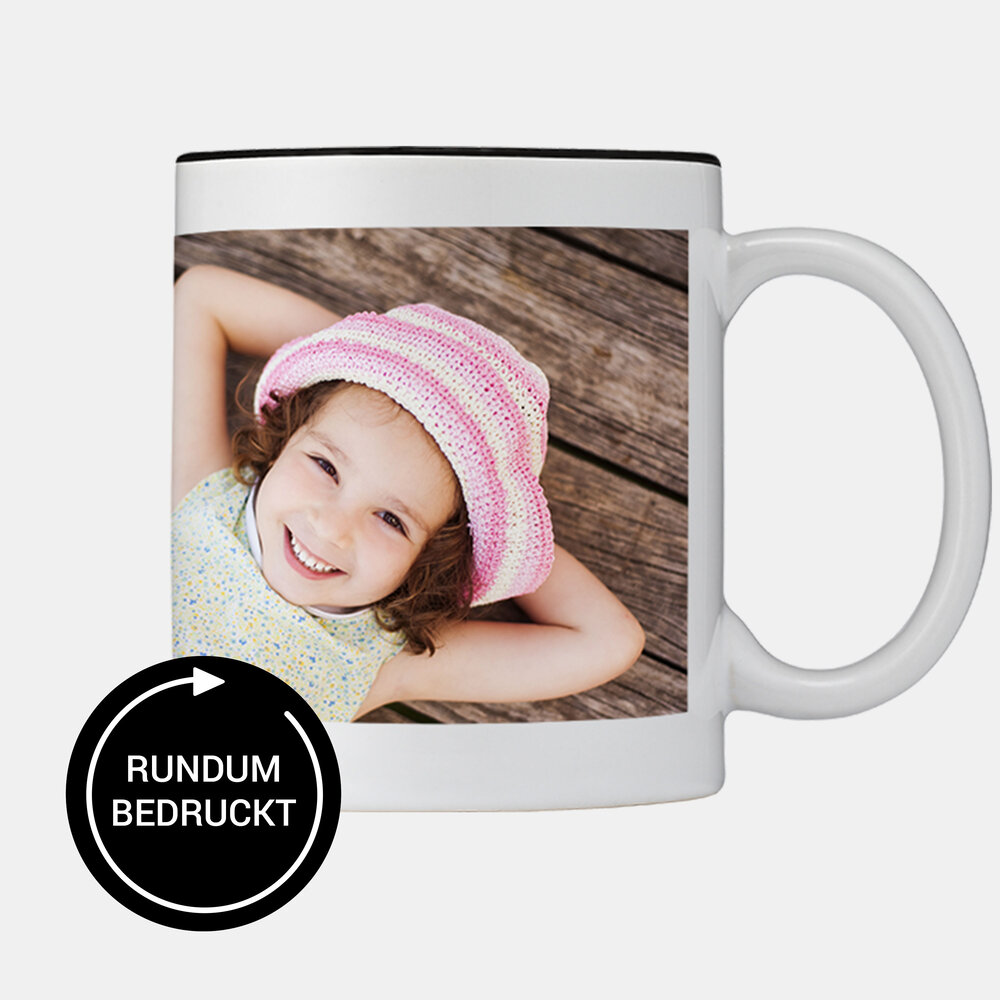 Die Panoramatasse mit schwarzer Innenseite zeigt ein Kind mit Sommerhut auf Holzuntergrund und ist rundum bedruckt.