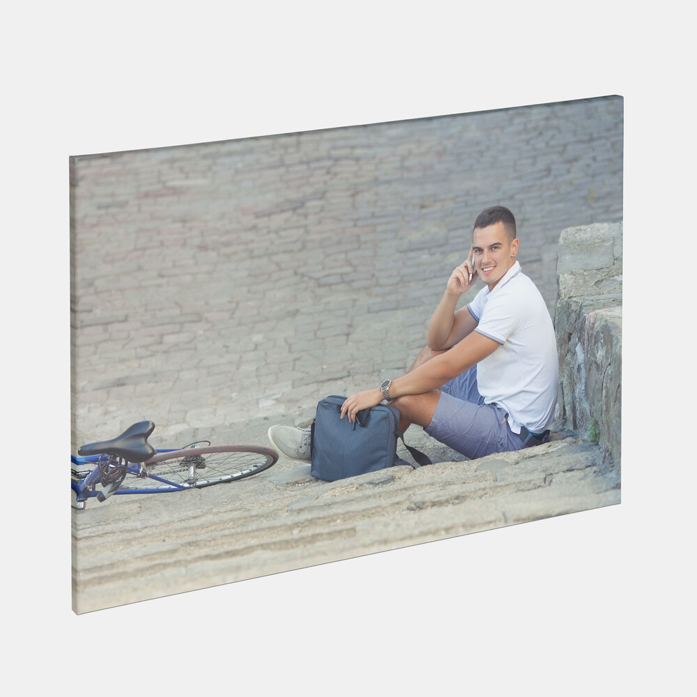 Auf der Leinwand ist ein Motiv mit einem jungen Mann zu sehen, der auf einer Steintreppe sitzt und telefoniert.